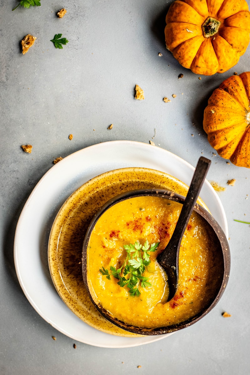 bowl of soup near two pumpkins